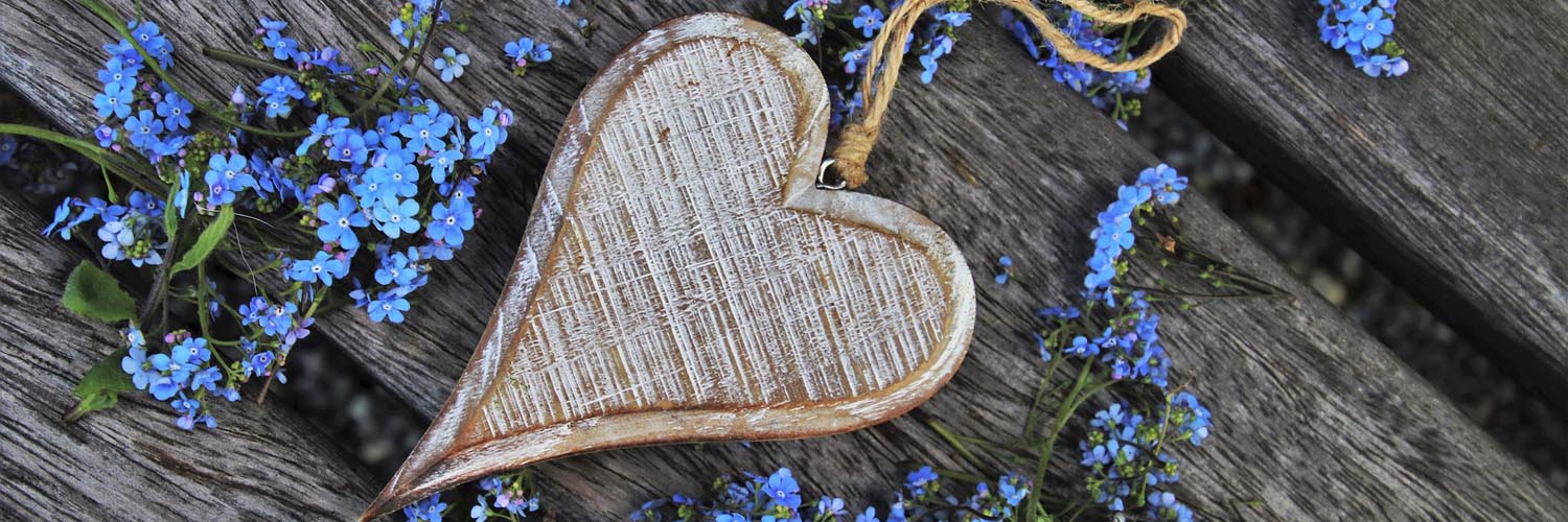 Image of a crafted heart surrounded by periwinkle flowers.